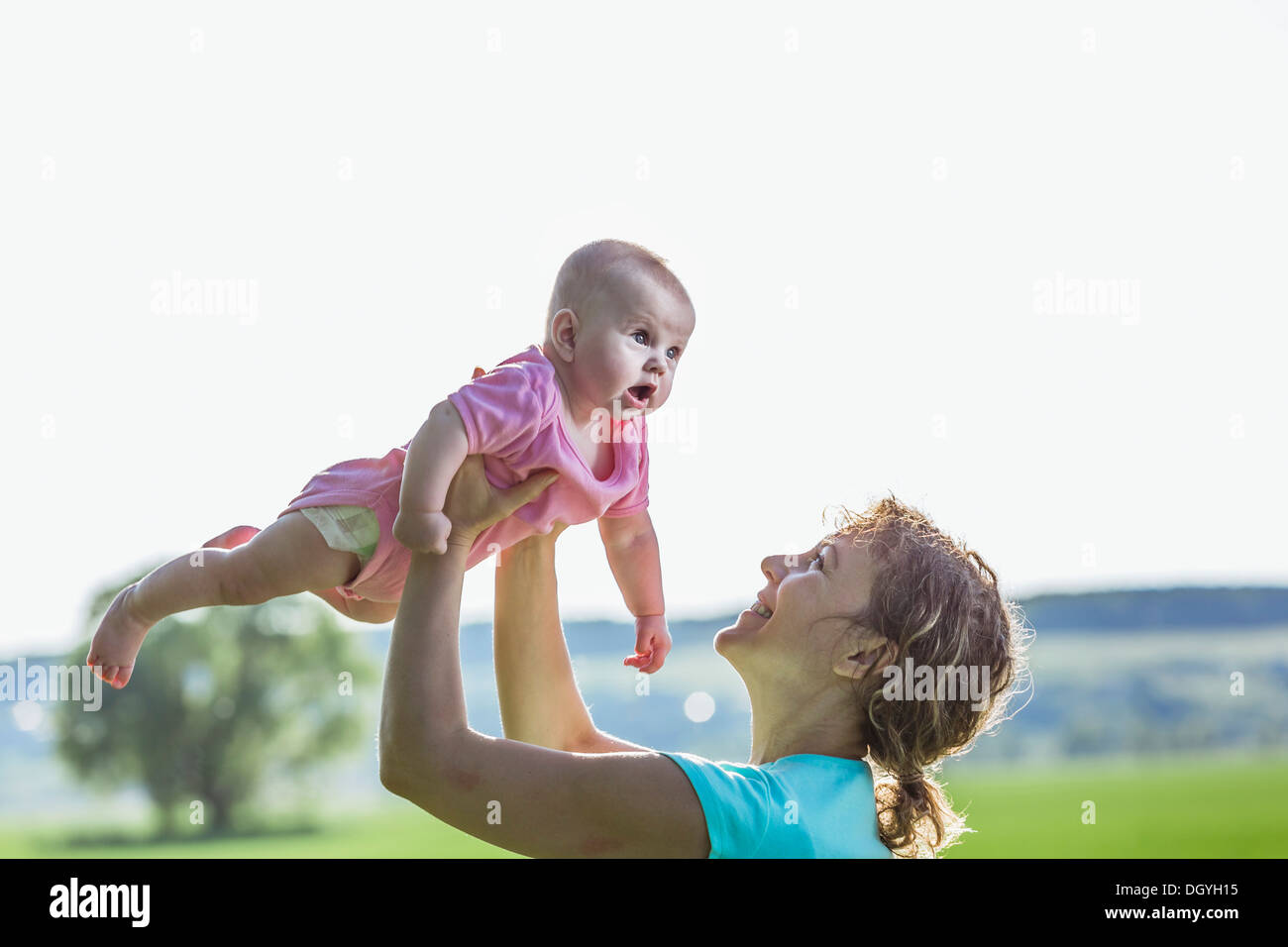 Eine fröhliche Mutter hält ihr Baby empor Stockfoto