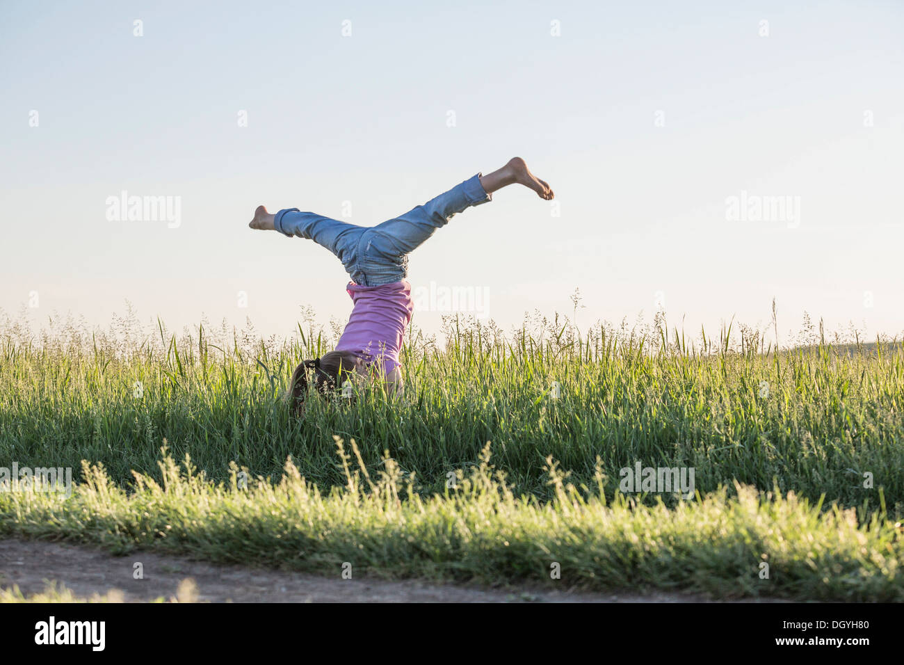 Ein junges Mädchen macht einen Handstand mit ihre Beine auseinander in einer Spaltung Stockfoto