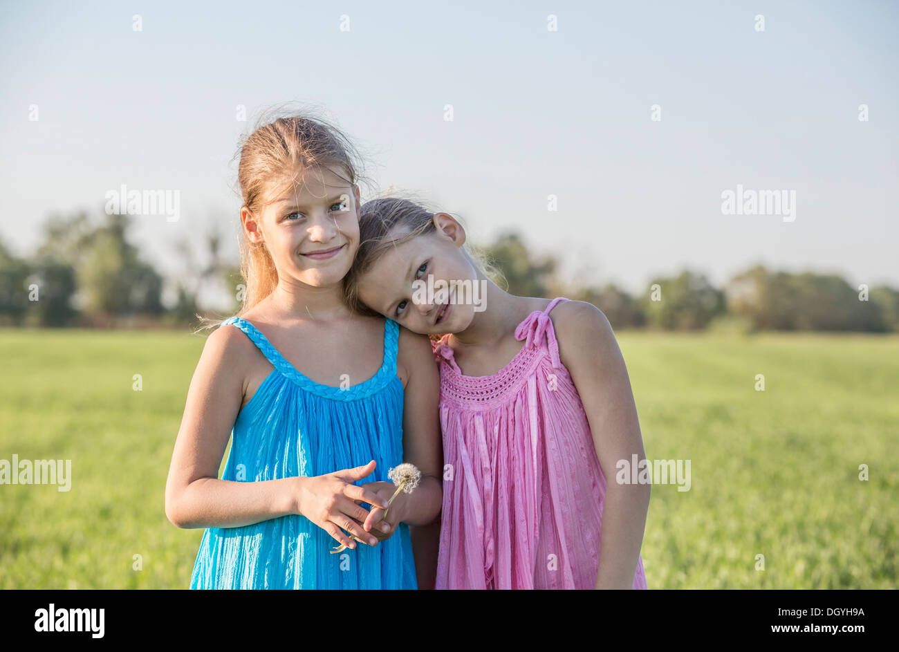 Zärtliche Zwillingsschwestern stehend in einem sonnigen Bereich Stockfoto