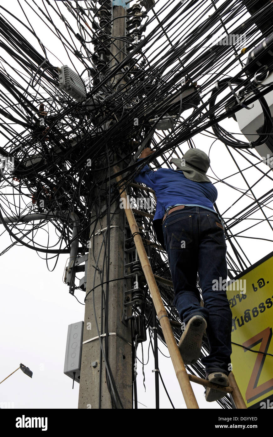 Mann klettert eine Leiter zu beheben macht Linien, Pylon, Chiang Mai, Thailand, Asien Stockfoto