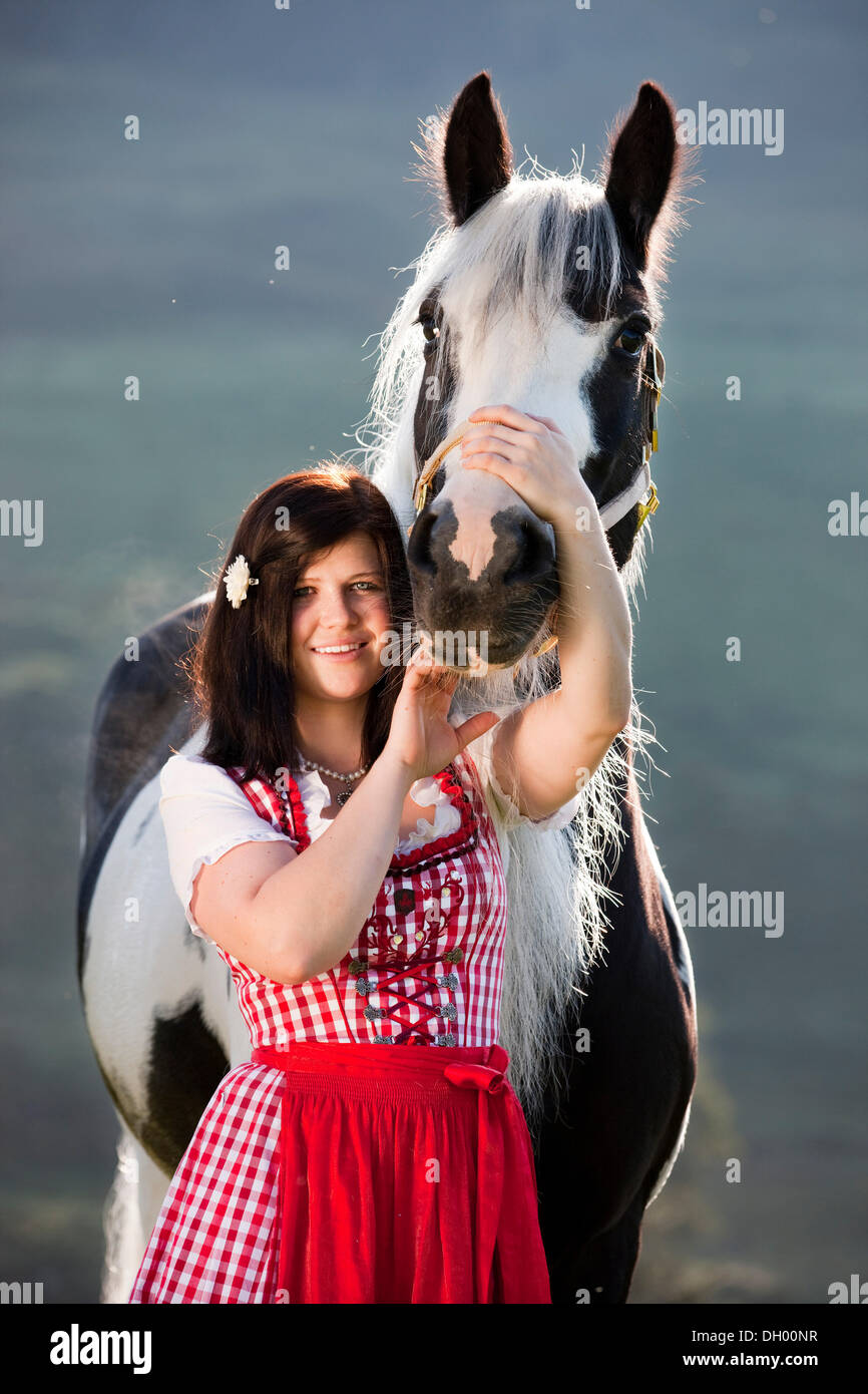 Junge Frau trägt ein Dirndl kuscheln mit einem Gypsy Vanner oder Tinker Pferd, Pinto, schwarz und weiß, Nord-Tirol, Austria, Europe Stockfoto