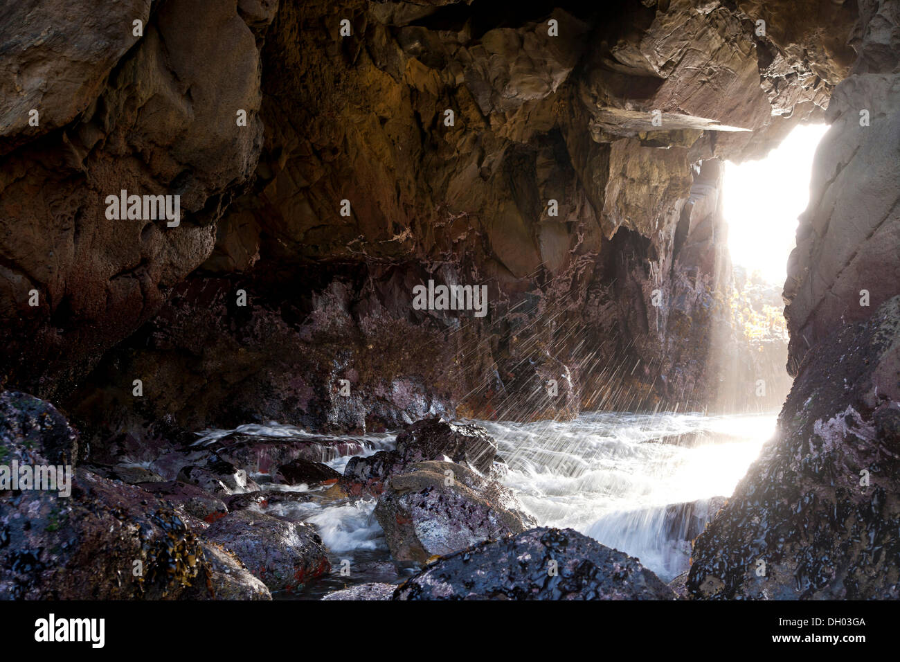 Surf und ein Strahl von Licht an der felsigen Küste von Pfeiffer Beach, Julia Pfeiffer Burns State Park, Big Sur, Kalifornien Stockfoto