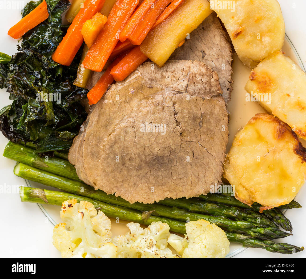 Traditionelle britische Sonntag Mittagessen - Roastbeef, Kartoffeln, Karotten, Pastinaken, Spargel, Grünkohl und Blumenkohl auf einer Platte Stockfoto