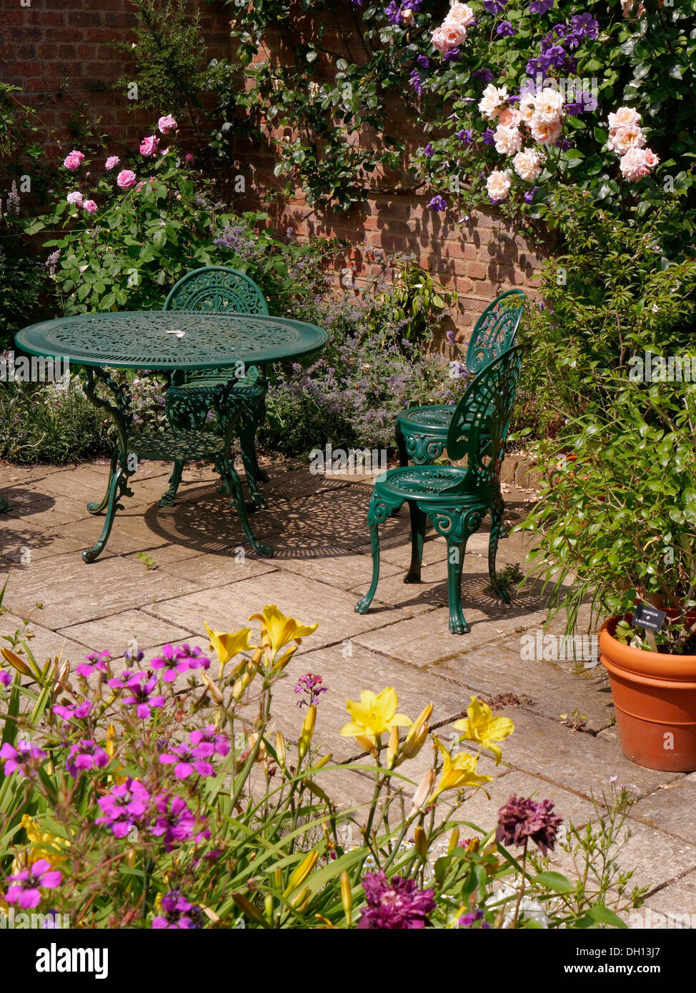 Attraktive gepflastert sonnigen Gartenterrasse mit grünen Metall Tisch und Stühle, Barnsdale Gärten, Oakham, Rutland, England, UK. Stockfoto