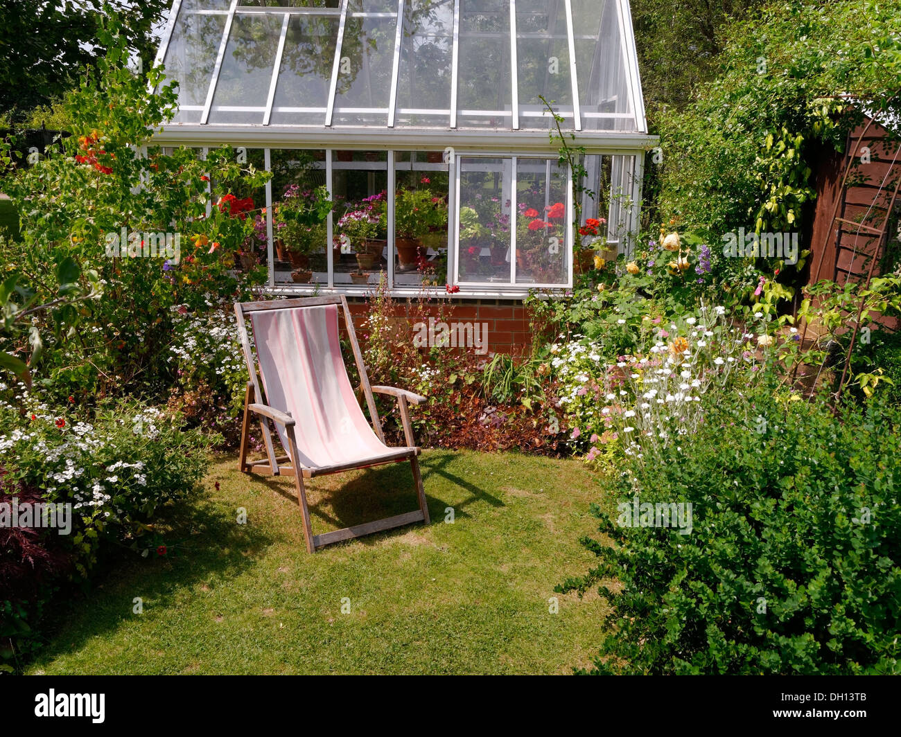 Kleine Rasenflächen Garten mit Grenzen, Liegestuhl und Gewächshaus, Barnsdale Gärten, Oakham, Rutland, England, UK. Stockfoto