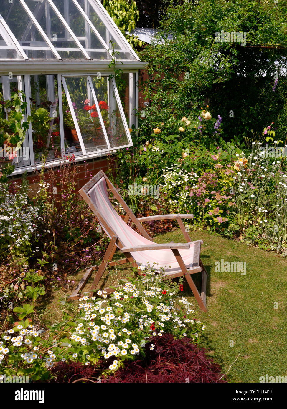 Kleine Rasenflächen Garten mit Grenzen, Liegestuhl und Gewächshaus, Barnsdale Gärten, Oakham, Rutland, England, UK. Stockfoto