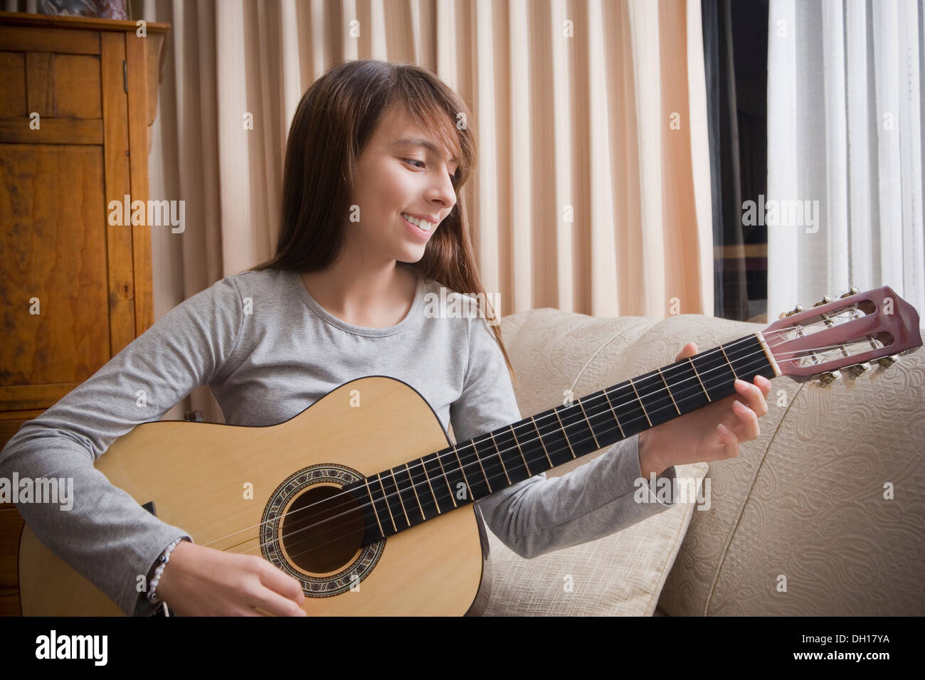Hispanischen Mädchen spielt Gitarre auf sofa Stockfoto