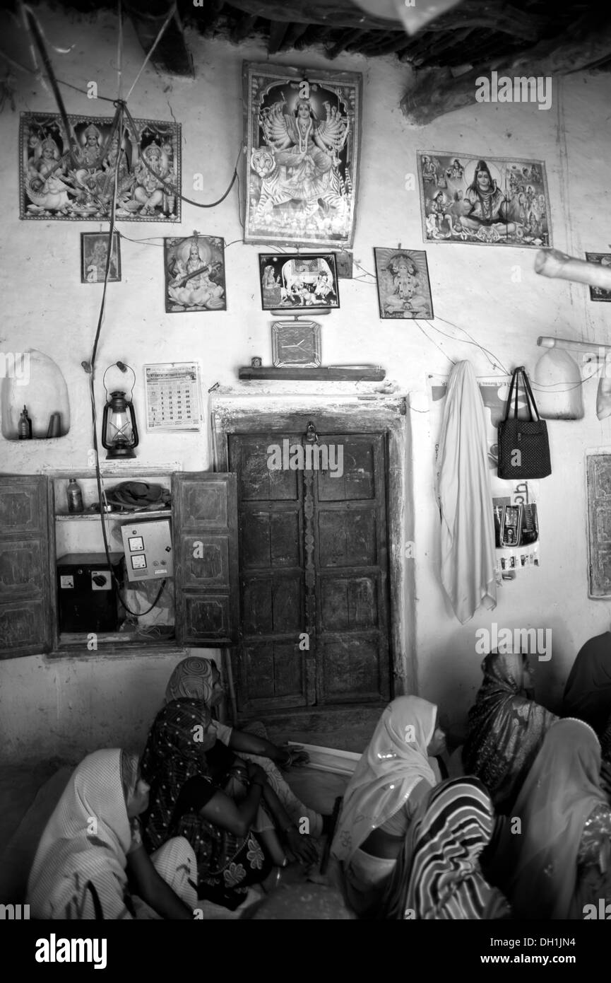Wand des Dorfhaus mit Postern von Göttern Petroleum Laterne Tasche Kleidung Tür Uttar Pradesh Indien Asien Stockfoto