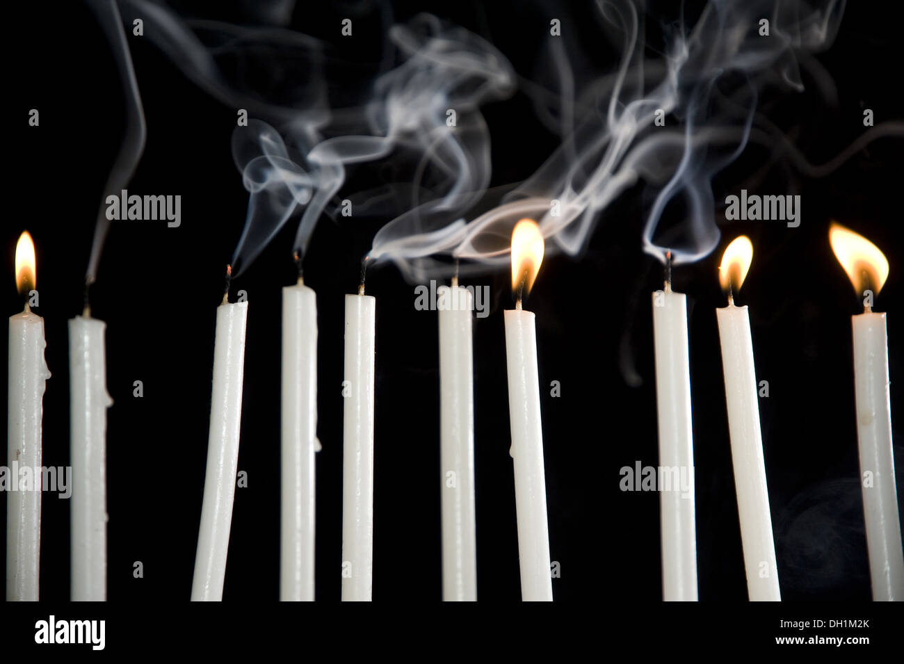 zehn brennende weiße Kerzen ausgeblasen, schwarzer Hintergrund Stockfoto