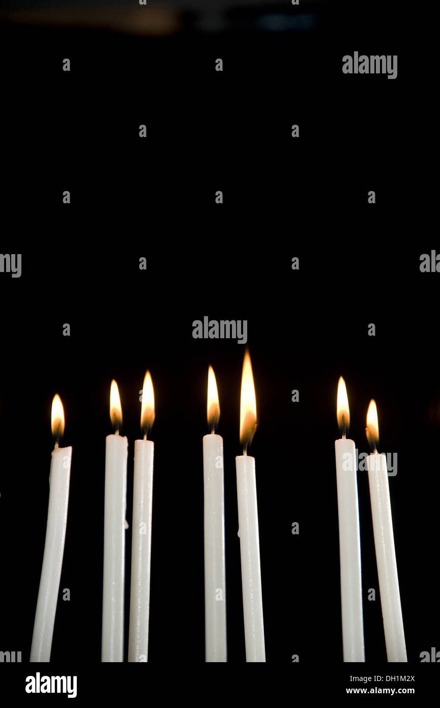 sieben weiße brennenden Kerzen Flamme schwarzen Hintergrund Stockfoto