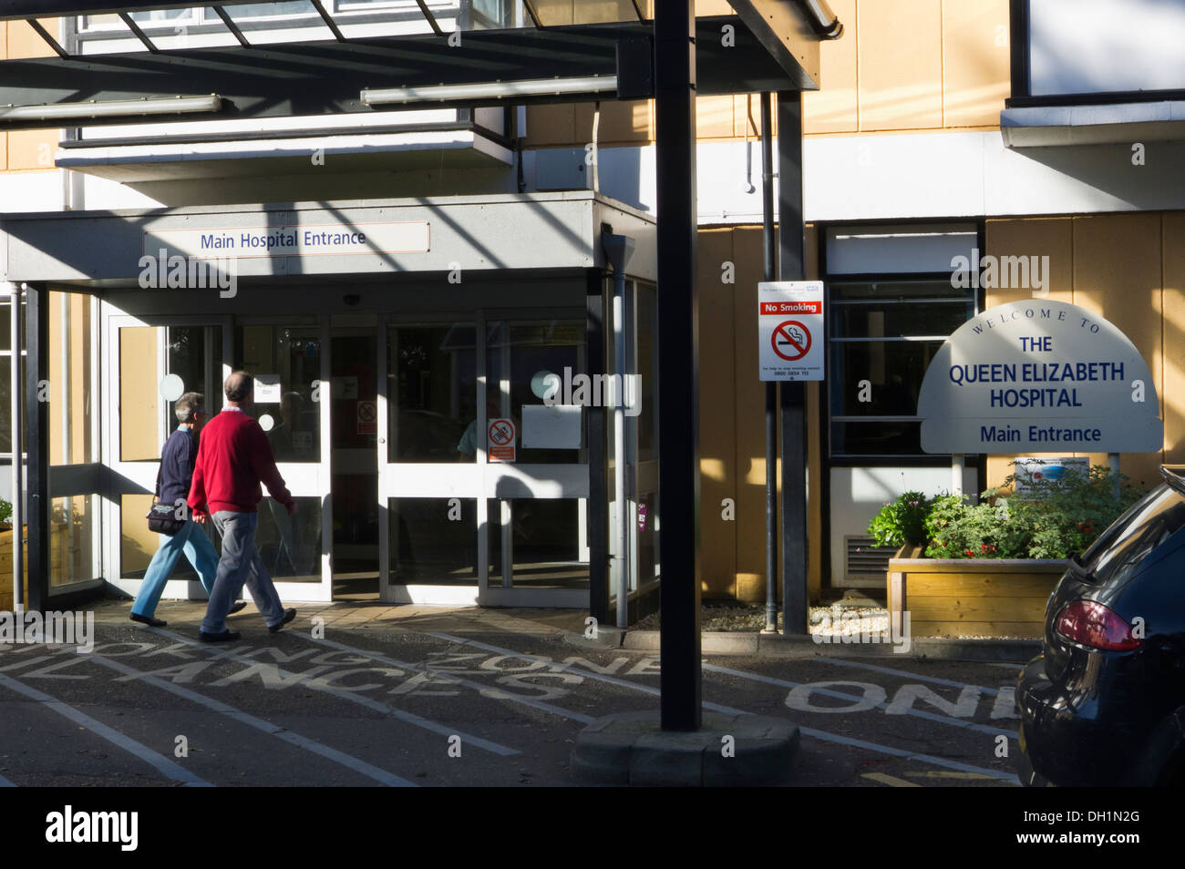 Mann und Frau zu Fuß in der Haupteingang für den Königin-Elisabeth-Hospital in King's Lynn, Norfolk. Stockfoto