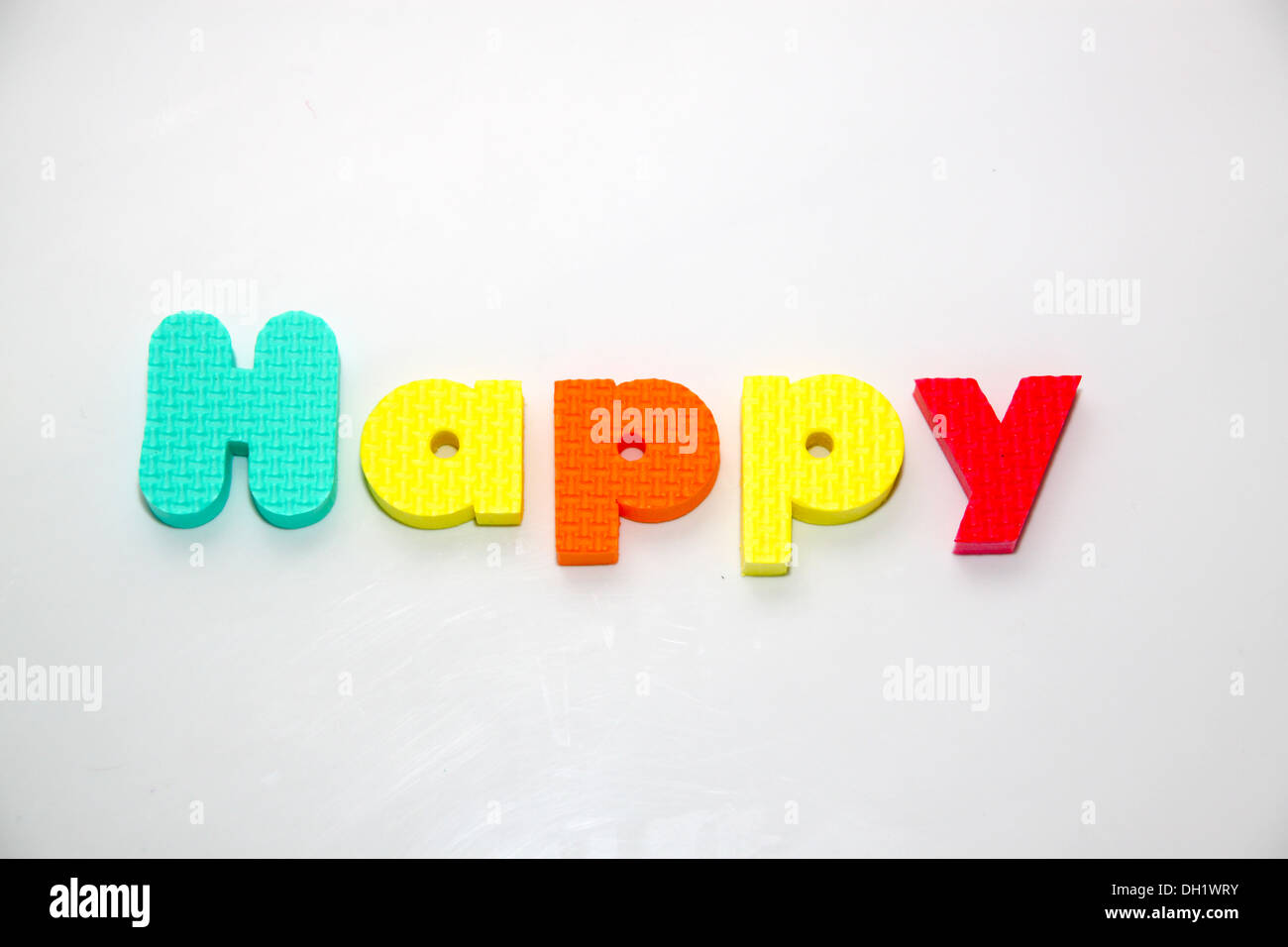 das Wort glücklich in bunten Kunststoff-Schaum Spielzeug Buchstaben ausgeschrieben Stockfoto