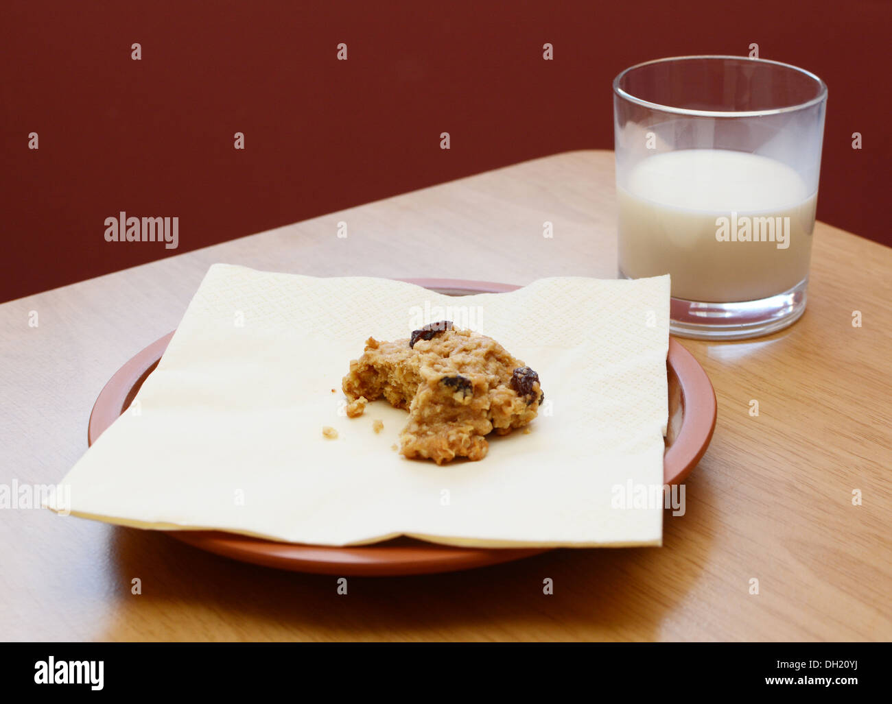 Hälfte gegessen Haferflocken Rosinen Cookies mit einem halben Glas Milch getrunken Stockfoto