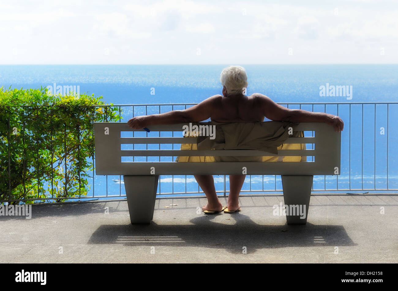 Funchal Madeira. Ein senior woman sonnen sich in der Mittagssonne mit Blick über den Atlantik Stockfoto