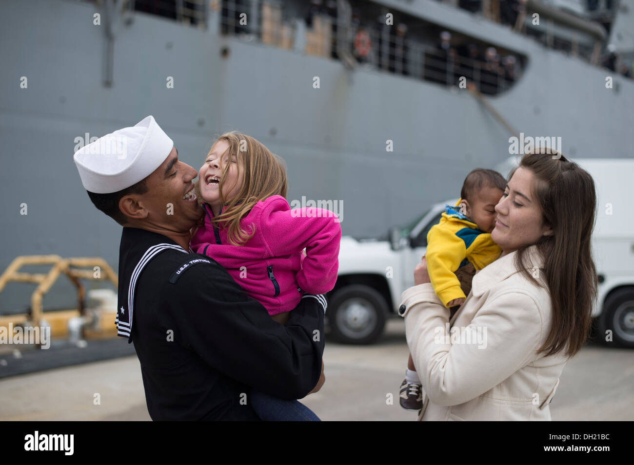Ein Seemann grüßt seine Familie wie die amphibischen Dock Landungsschiff USS Tortuga (LSD 46) von Flotte Aktivitäten Sasebo zurück. Tortuga wurde als gut vorwärts-bereitgestellt von USS Ashland (LSD-48) ersetzt. Stockfoto