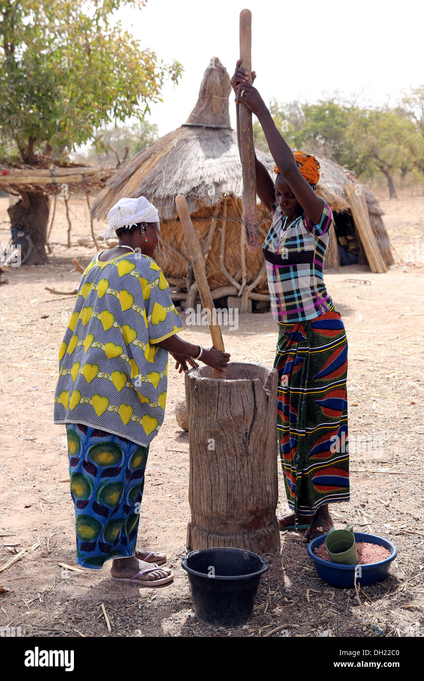 Frauen, die Hirse in einem hölzernen Mörser stampfen. Dorf Sissénin in der Nähe von Koudougou, Burkina Faso, Afrika Stockfoto