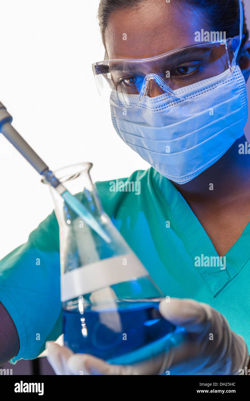 Asiatische medizinische oder wissenschaftliche Forscherin oder Arzt mit Hilfe einer Pipette & konischen Kolben blaue Lösung in einem Labor Stockfoto