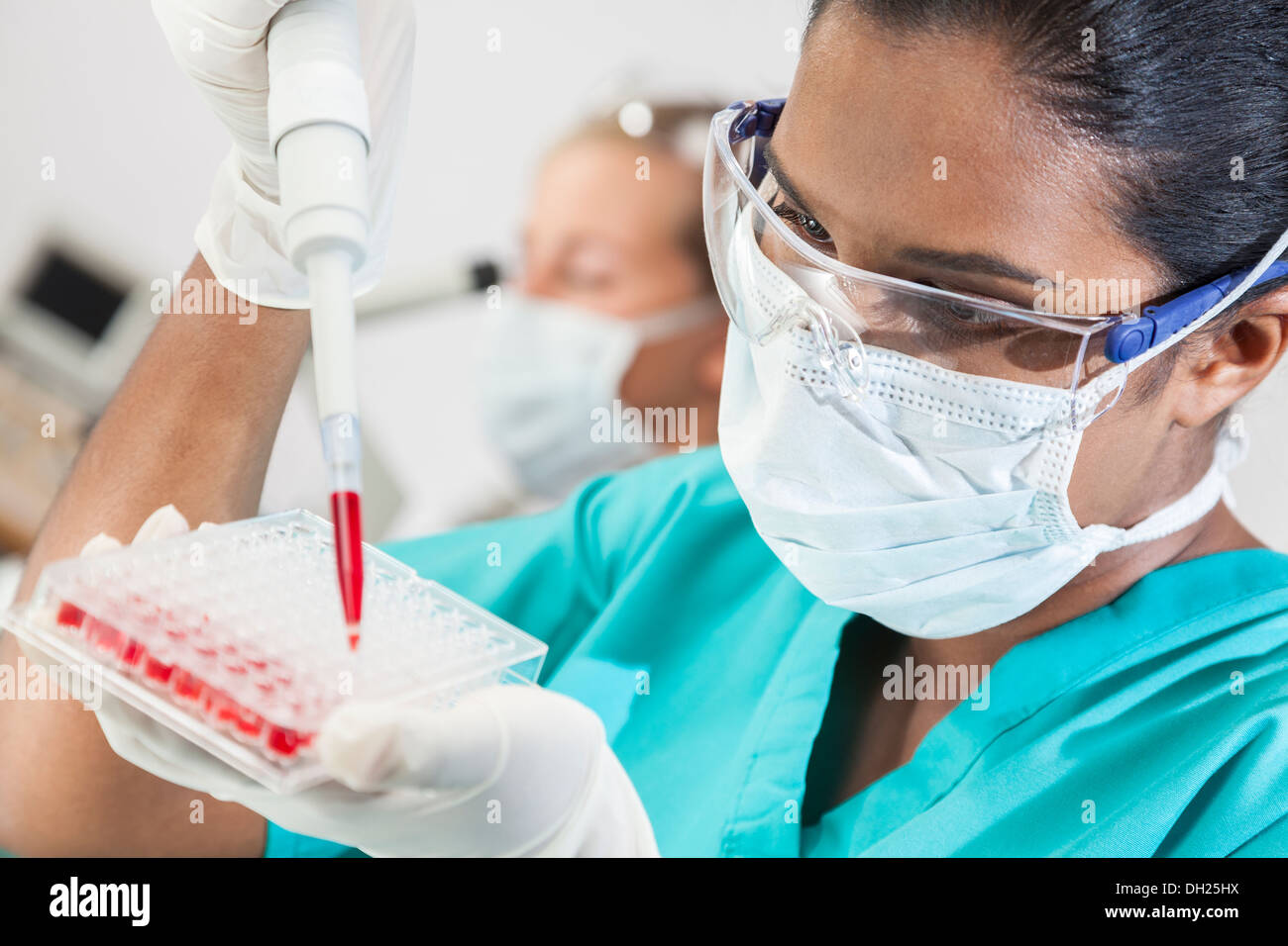 Asiatische medizinische oder wissenschaftliche Forscherin oder Arzt über eine Pipette und Probe Fach Blutprobe im Labor testen Stockfoto