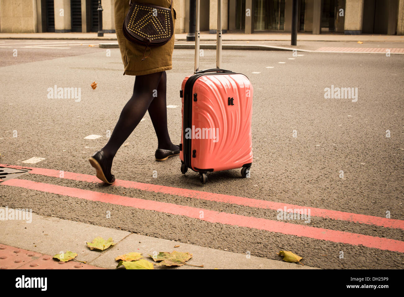 Junge Frau Räder ihren rosa Koffer über Straße Stockfoto