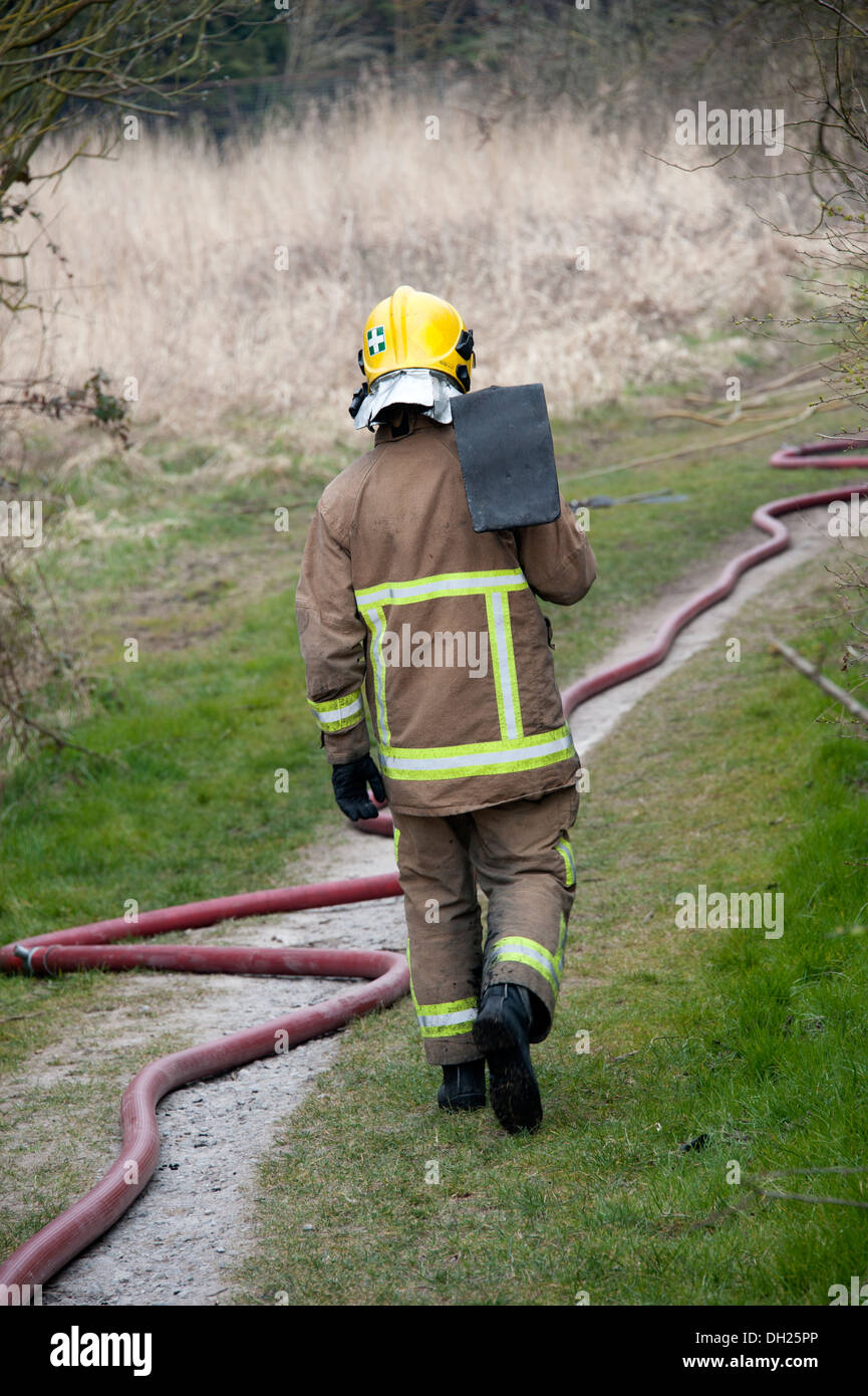 Feuerwehrmann mit Schläger Rasen Feuer Stockfoto