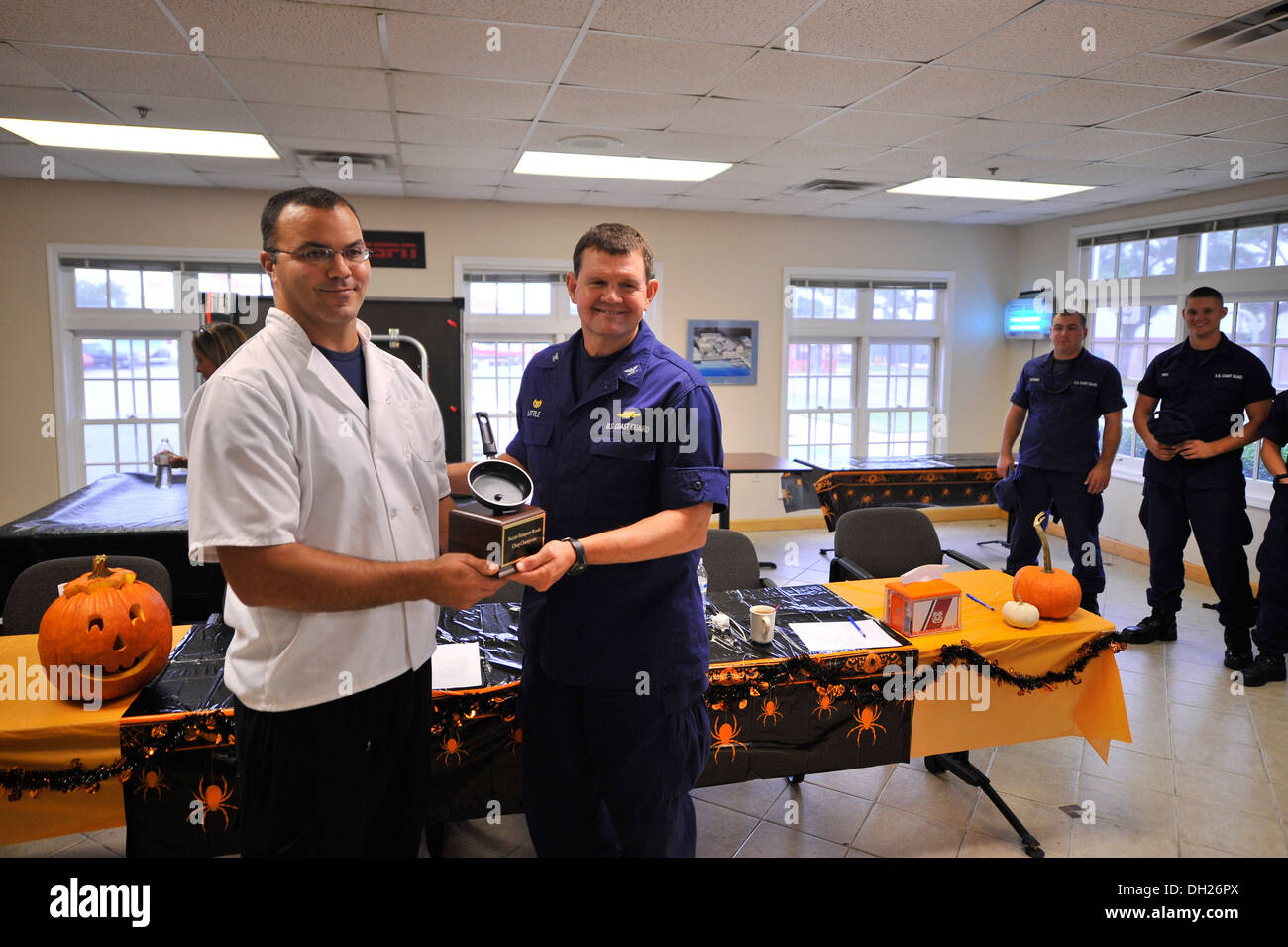 Captain John Little der Kommandant der Küstenwache Bereich Hampton Roads, präsentiert Petty Officer 2. Klasse David Blonn, ein Food-Service-Spezialist vertritt die Coast Guard Cutter Albacore, die Chop champions Trophy für den Gewinn der Kochwettbewerb Monda Stockfoto