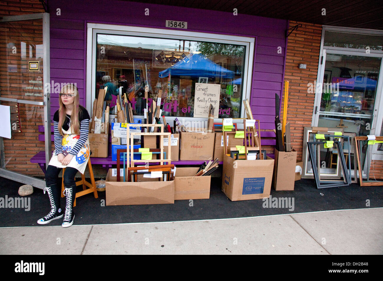 Junge Frau sitzt vor ihrem Rahmen-Shop Converse Chuck Taylor One Star high Tops tragen.  Hayward Wisconsin WI, USA Stockfoto