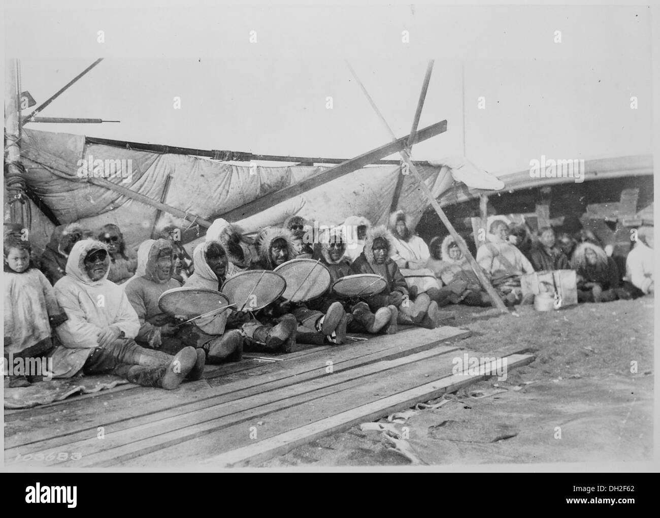 Das Bild zeigt ein Eskimo-Tanzorchester in Point Barrow, Alaska, mit Trommelköpfen aus Walmägen, die die traditionelle Eskimo-Kultur und musikalische Praxis von 1935 widerspiegeln. Die Instrumente heben den Einfallsreichtum und das kulturelle Erbe der Gemeinschaft hervor. Stockfoto