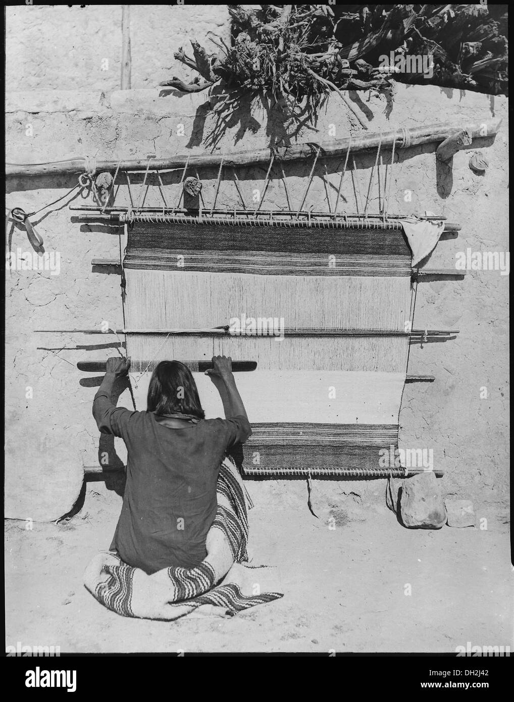 Ein Navajo-Weber spinnt Wolle zu Garn, während er an einem Webstuhl in Torreon, New Mexico, sitzt und dabei traditionelle Handwerkskunst zeigt. Stockfoto