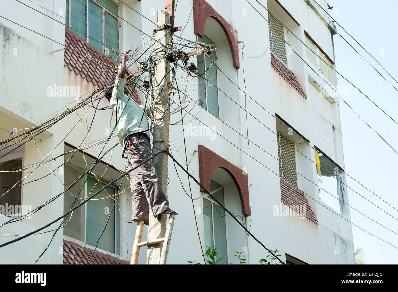 Indische Elektriker arbeiten bis ein Strommast in den Straßen von Puttaparthi, Andhra Pradesh, Indien Stockfoto