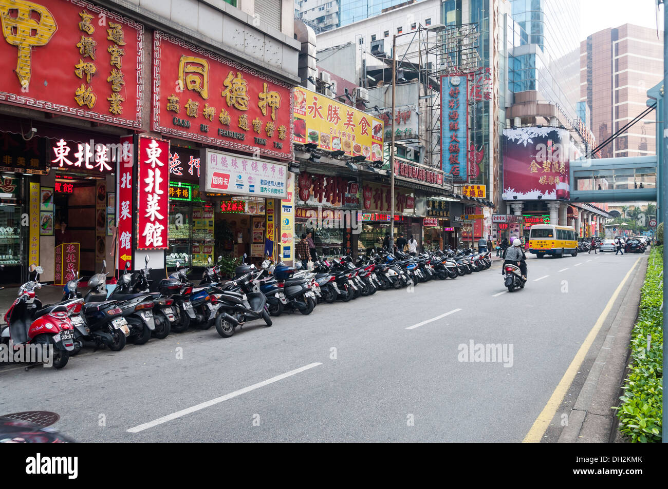 Eine lange Reihe von Motorrollern auf einer Straße in Macau. Stockfoto