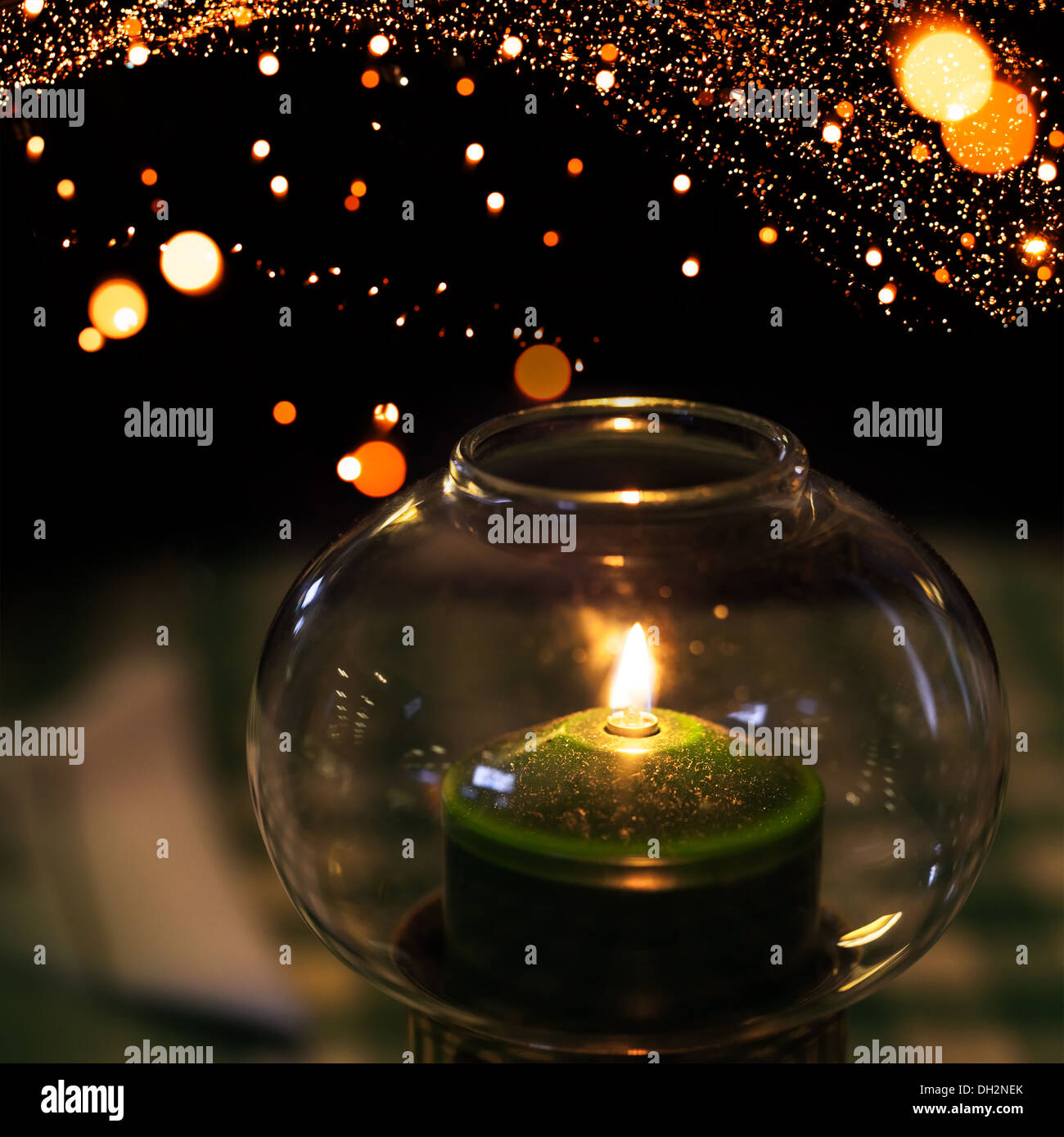 Grüne Kerze brennt in Leuchter aus Glas mit Weihnachten Lichter Bokeh im Hintergrund Kranz gemacht Stockfoto