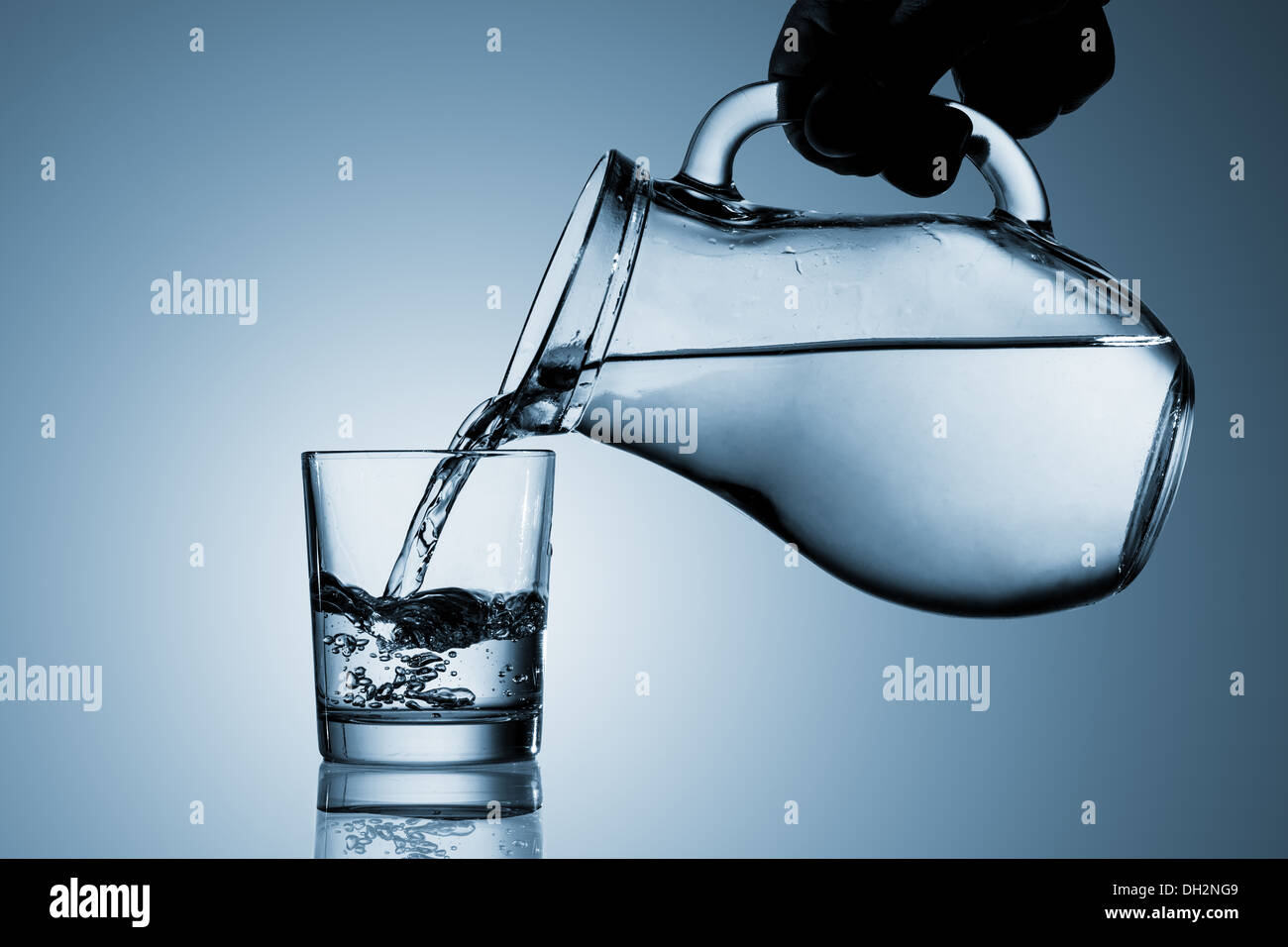 Wasser aus einem Krug in ein Glas gießen Stockfoto