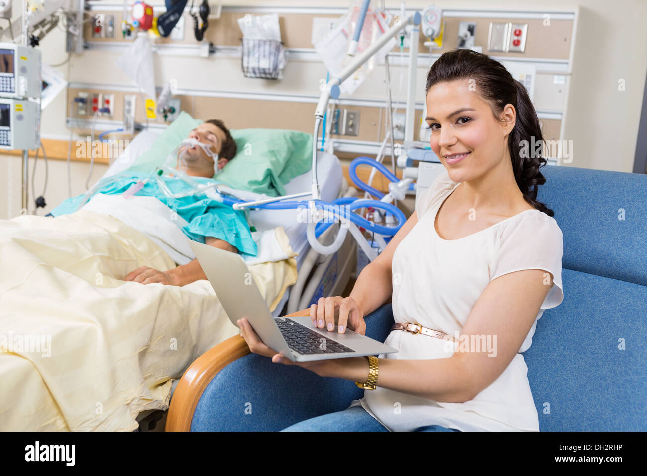 Frau mit Laptop sitzen durch männliche Patienten im Krankenhaus Stockfoto