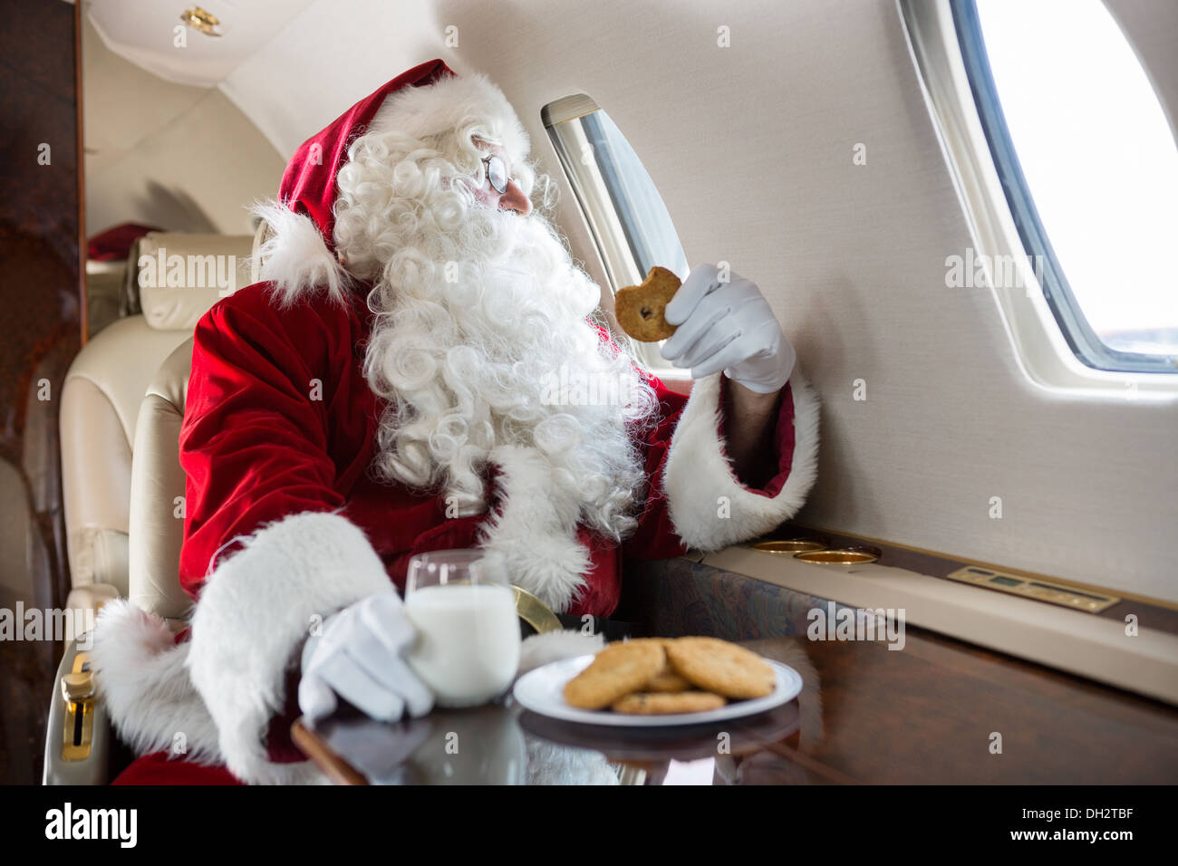Santa Cookie beim Blick durch Private Jet Fenster halten Stockfoto