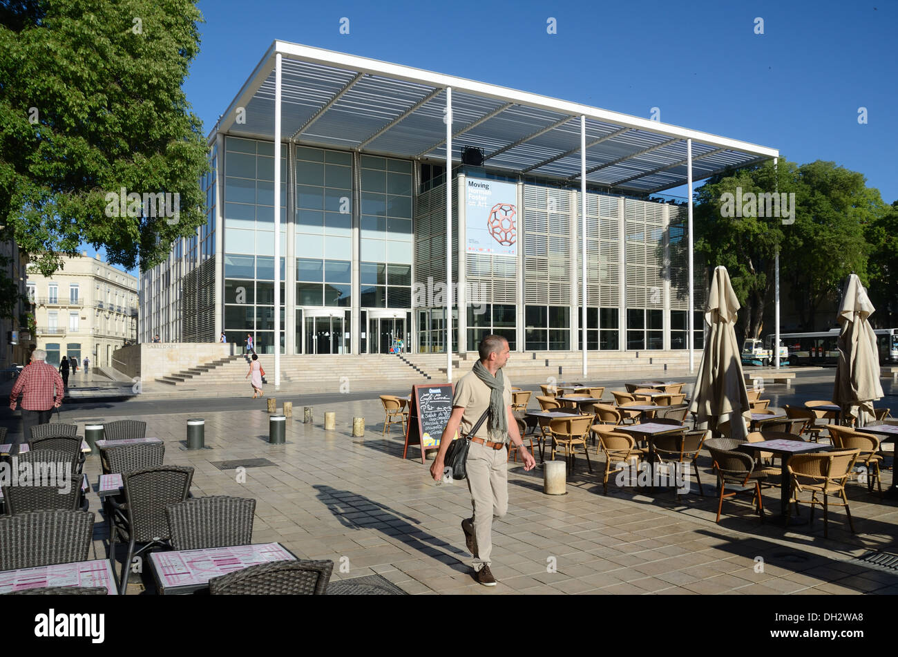 Man Spaziert vor dem Carré d'Art Musée d'Art Contemporain Modern Art Museum von Norman Foster und Pavement Café Nimes Gard France Stockfoto