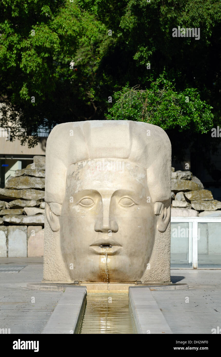 Moderne öffentliche Skulptur von Giant Head als Straßenbrunnen des Gottes Nemausus Place d'Assas Nimes Frankreich Stockfoto