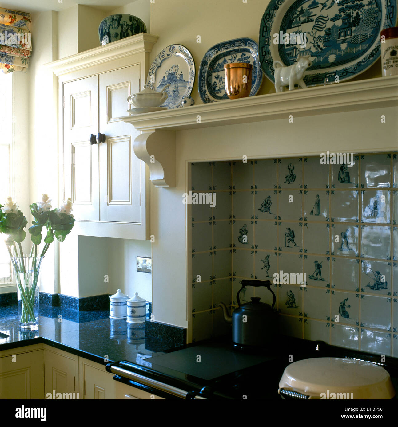 Nahaufnahme der blaue + weiße Platten auf Regal und blaue + weiße Delft-Stil  geflieste Wand über Aga-Ofen mit schwarz Wasserkocher im Landhaus-Küche  Stockfotografie - Alamy