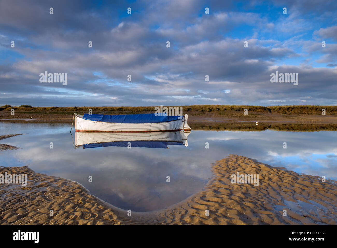 Boot und Reflexionen im Stillwasser am Burnham Overy Staithe, Norfolk, England, November Stockfoto
