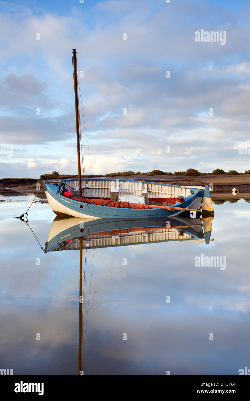 Boot und Reflexionen im Stillwasser am Burnham Overy Staithe, Norfolk, England, November Stockfoto