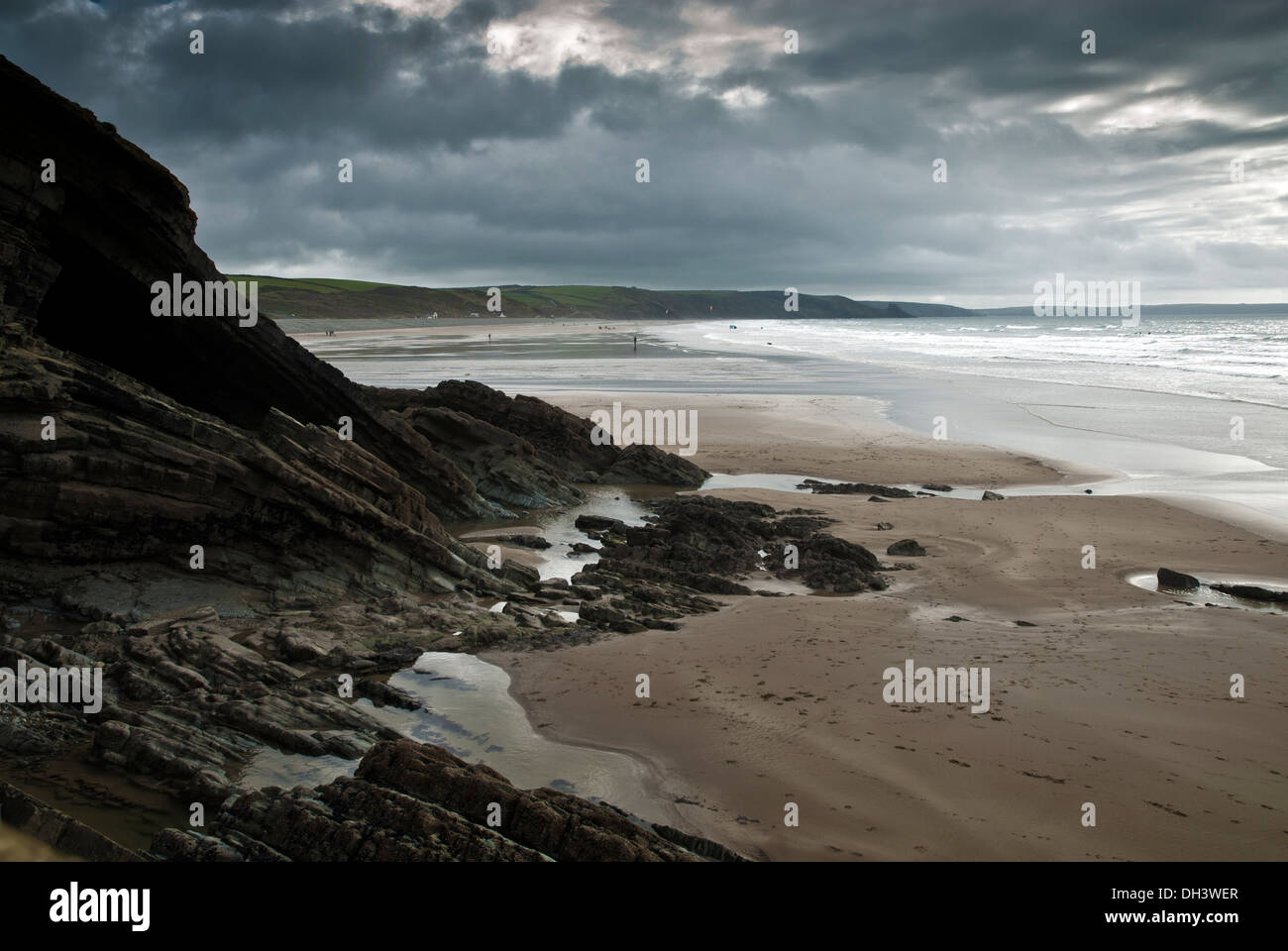 Newgale Sands in Pembrokeshire, Südwest-Wales umrahmt von einer felsigen Klippe und dramatischen Himmel bedeckt. Stockfoto