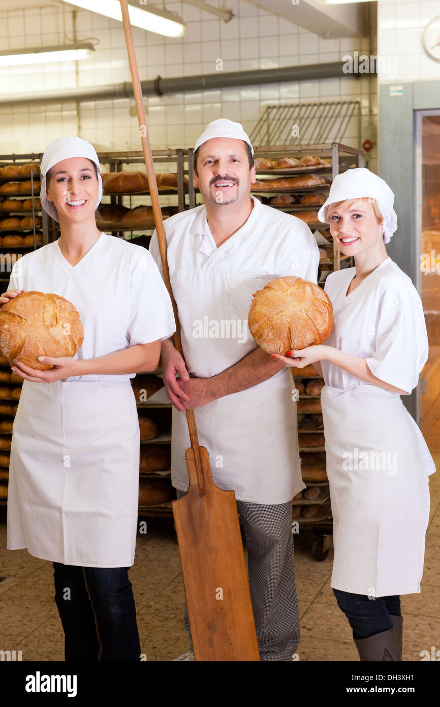 Baker steht mit seinem Team in der Bäckerei mit frisch gebackenem Brot ...