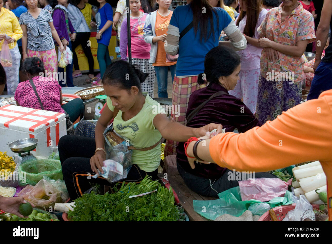 Frauen, die am nahe gelegenen Textilfabriken Arbeiten sind nach ihrer Schicht in Phnom Penh, Kambodscha Lebensmittel auf dem Markt kaufen. Stockfoto