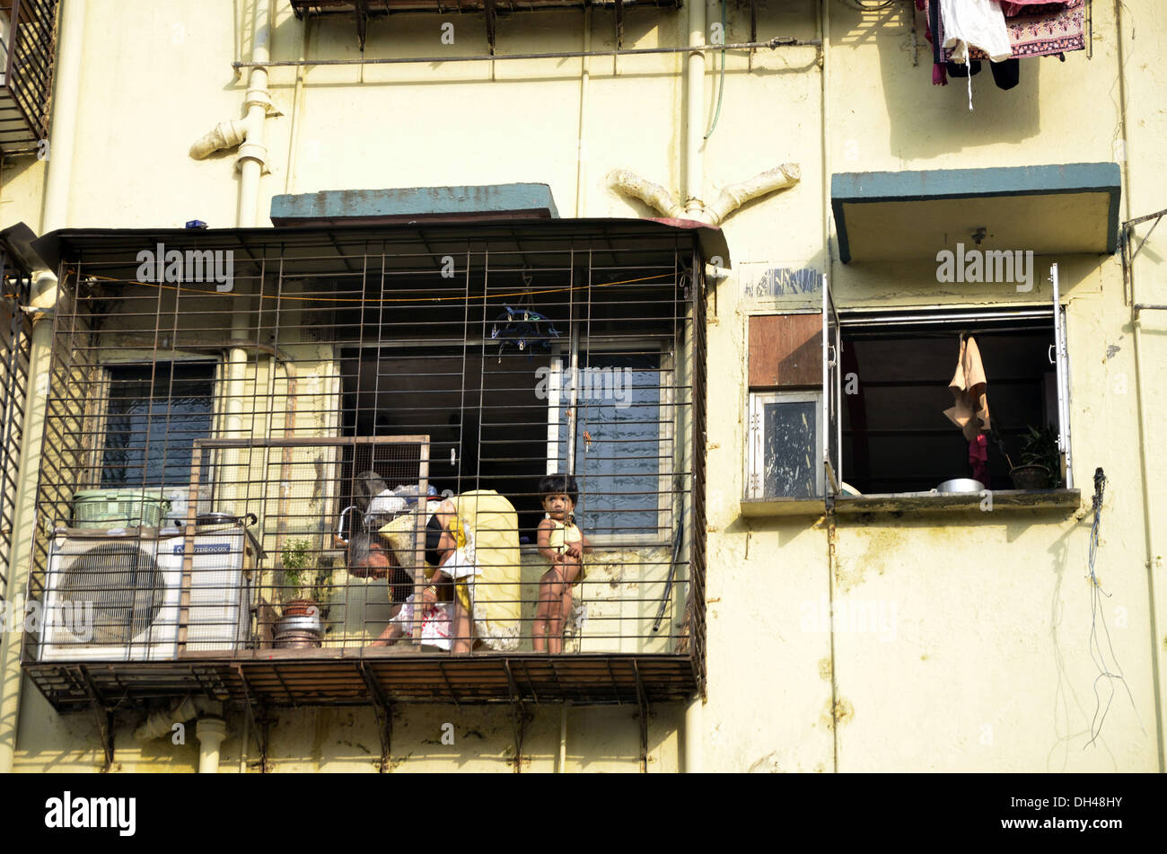 Alte Dame und Mädchen stehen im erweiterten Fenster grill Balkon flach Mumbai Maharashtra Indien Stockfoto