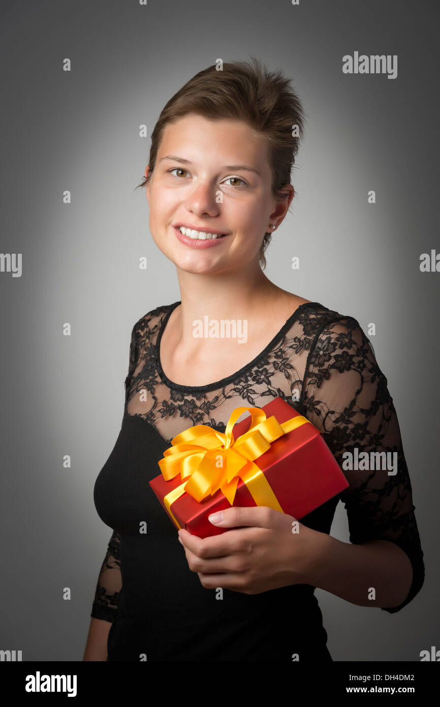 Junge Frau im Abendkleid mit einem roten Weihnachts- oder Geburtstagsgeschenk Stockfoto