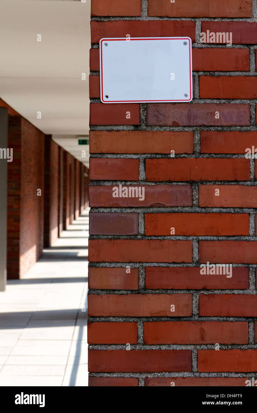 Leeres weißes Schild auf einer roten Backsteinmauer. Stockfoto