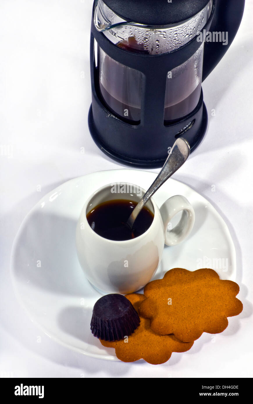Kaffee, traditionelle französische Presse Kaffeemaschine und kleine weiße Tasse mit einem silbernen Löffel, Kekse und Schokolade. Stockfoto