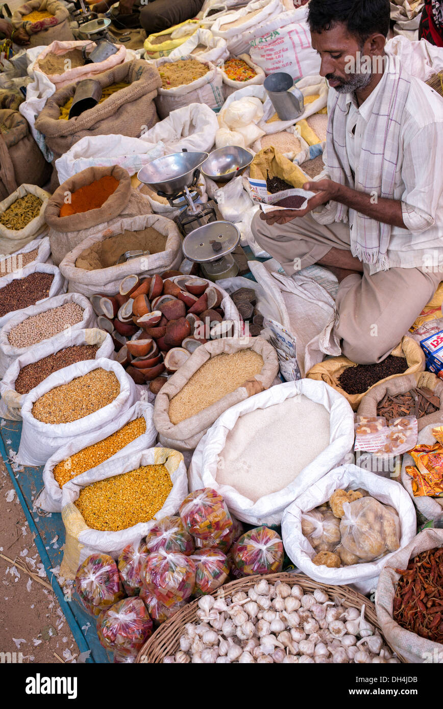 Indischer Mann verkauft Gewürze und getrocknete Produkte aus Säcken auf einem indischen Markt. Andhra Pradesh, Indien Stockfoto