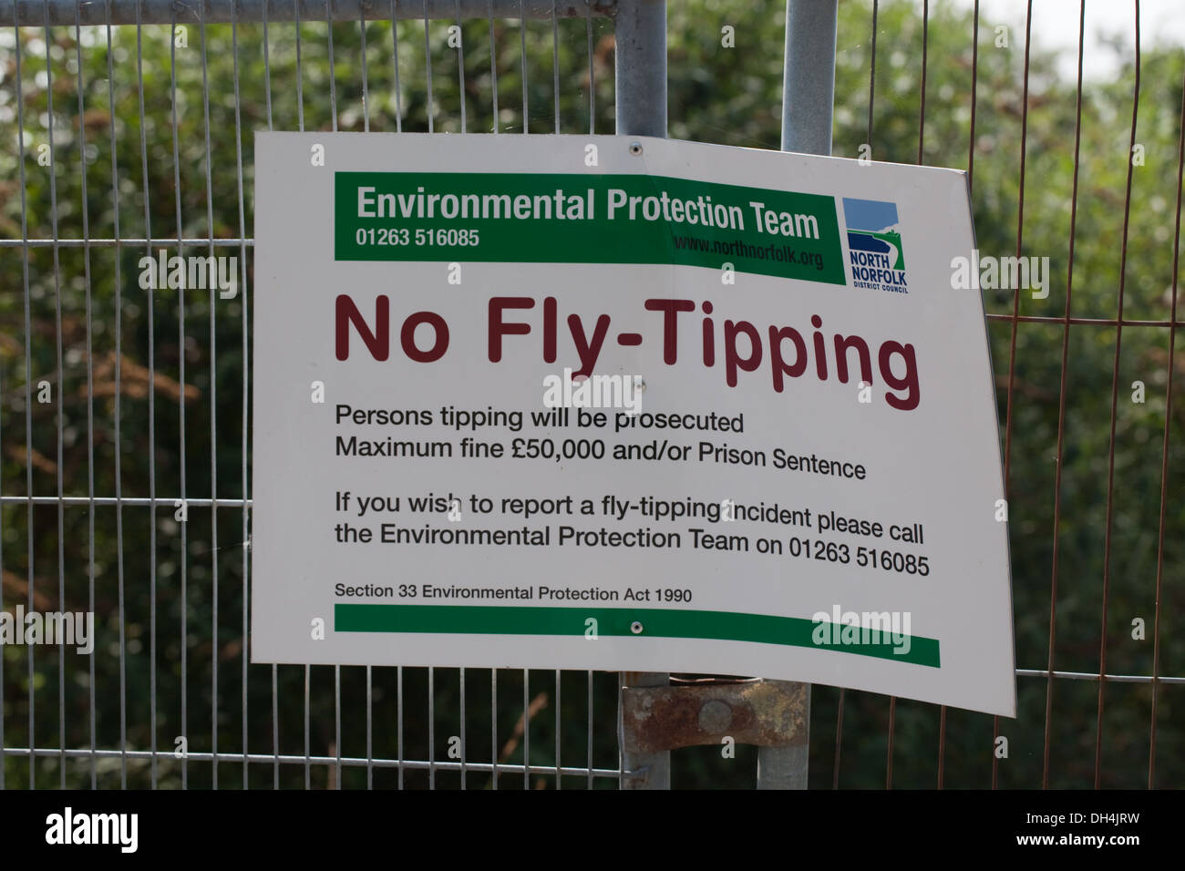 Zeichen; Lesen keine fliegen-Tipping. North Norfolk Gemeinderat. Sicherheitszaun um eine braune Wiese beigefügt. Stockfoto