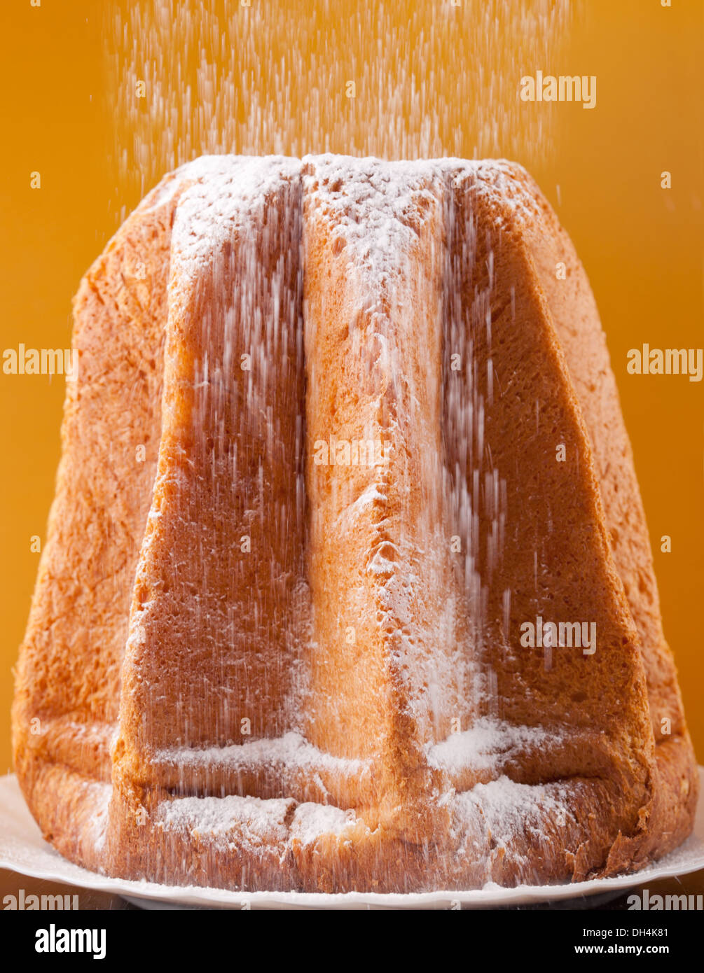 Pandoro mit Abstauben des Puderzucker auf orange Hintergrund Stockfoto