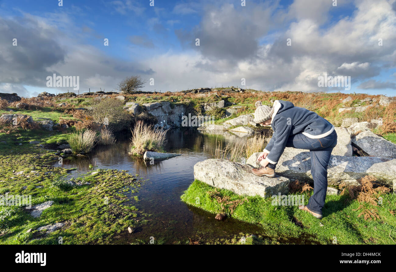 Eine Frau Wanderer stoppt, um ihre Schnürsenkel binden auf Bodmin Moor in Cornwall Stockfoto